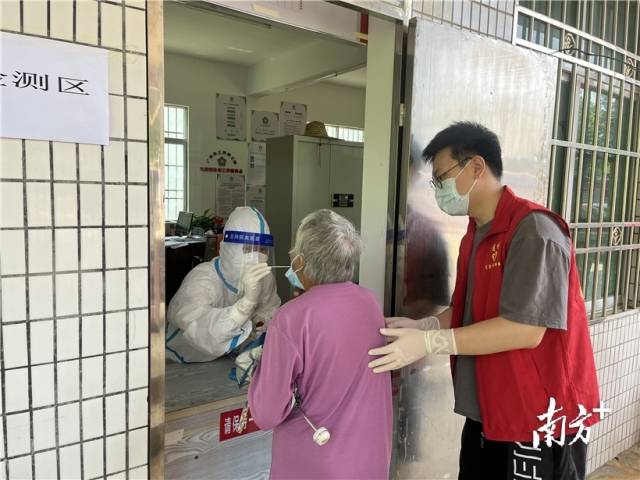 現(xiàn)場志愿者幫助行動不便群眾接受核酸檢測。